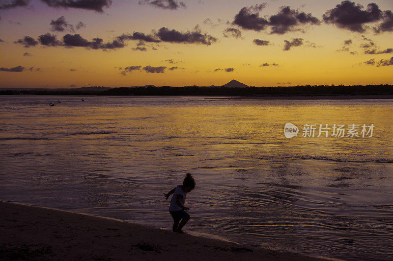 女孩在夕阳下沿着水边奔跑。