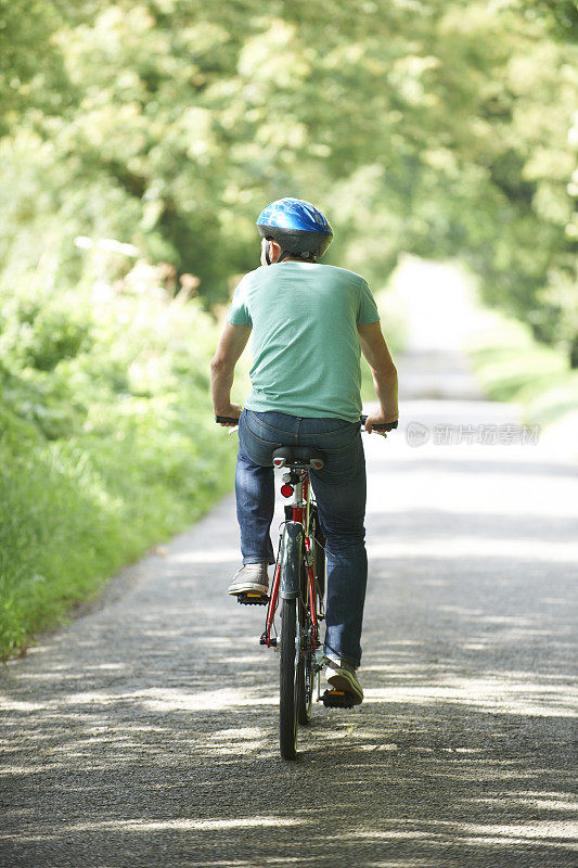 年轻人在农村骑自行车的后视图