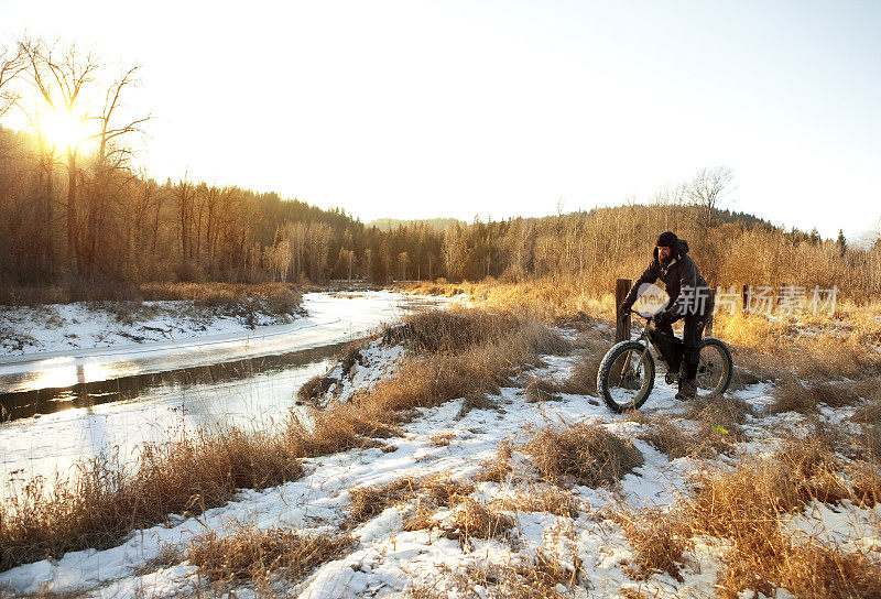 一个人骑着他的胖自行车沿着一条河的小径。