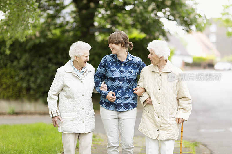 年轻的看护者帮助老年妇女在街上行走