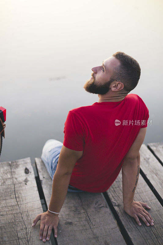 一个人坐在老木头码头上，看着湖面