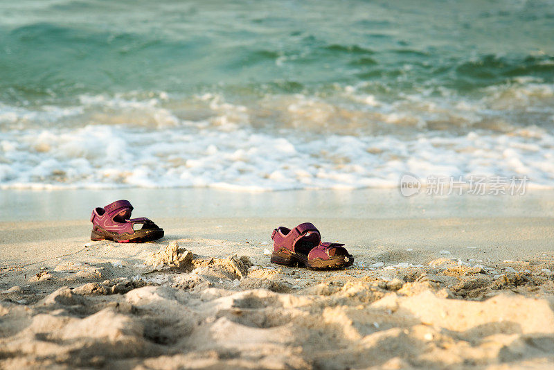 一双丢在沙滩上的小凉鞋