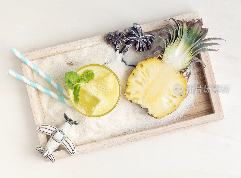 健康的菠萝饮料和玩具沙在木托盘