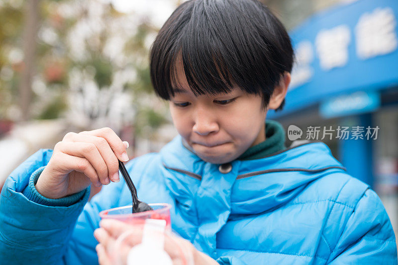 亚洲女孩在街上吃果酱很开心