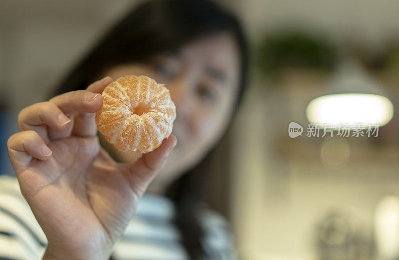 女孩拿着剥皮的橘子