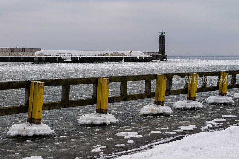 港口码头的灯塔。港口被冰覆盖着。冬天的季节。