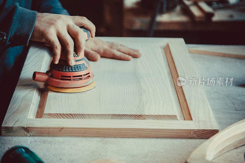 木匠使用砂光机木制家具的特写。软的焦点。浅景深。