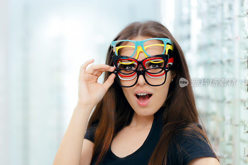有趣的女人尝试许多眼镜框在眼镜店