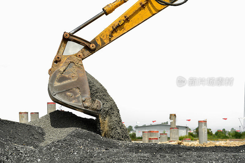 挖掘机在倒塌的建筑物上挖土。装满泥土、砖块和垃圾的桶。挖掘机在建筑工地工作。