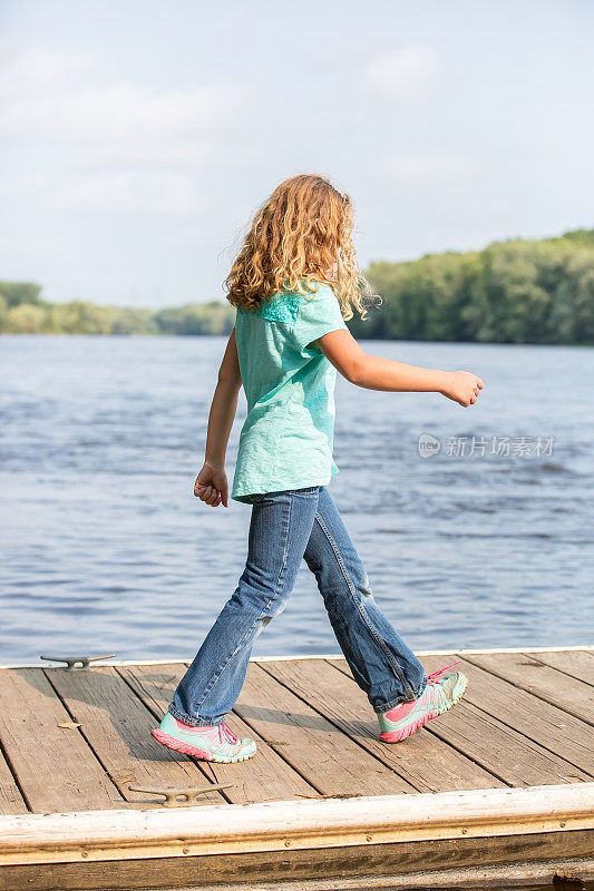 走在密西西比河木制码头上的年轻女孩