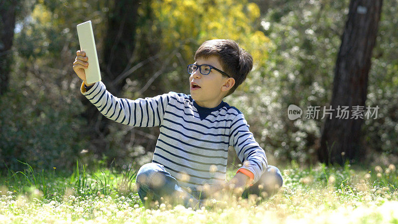快乐的孩子在森林中使用数字平板电脑