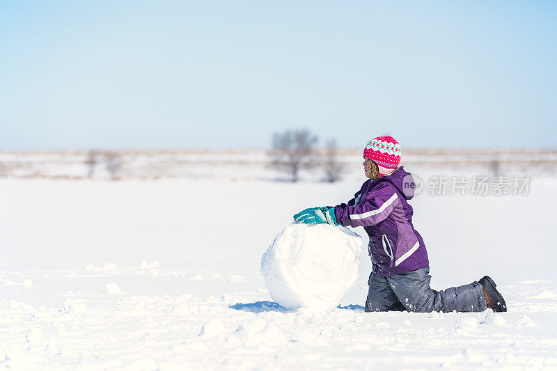 冬天，女孩在结冰的湖面上滚雪球