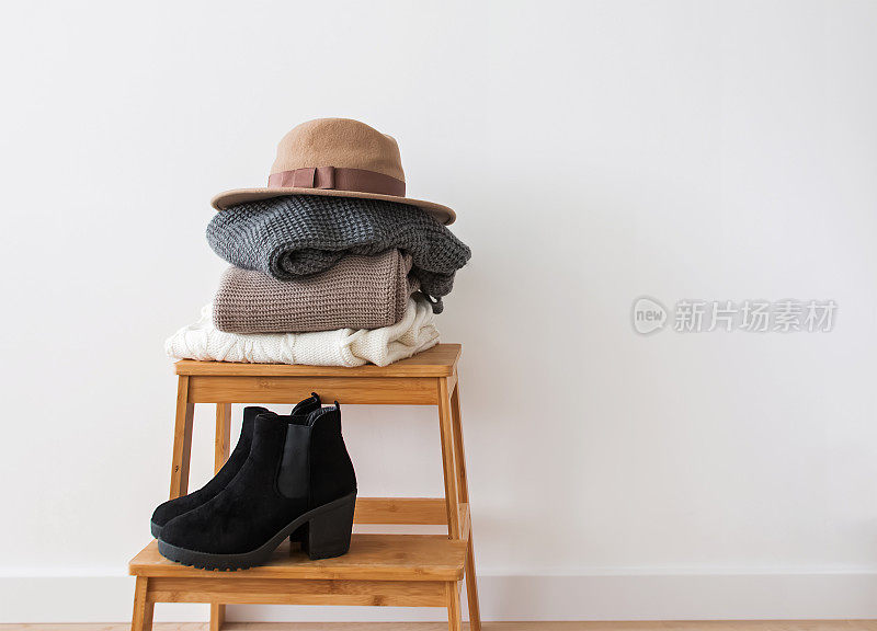 白墙附近堆放着针织毛衣、帽子和靴子。