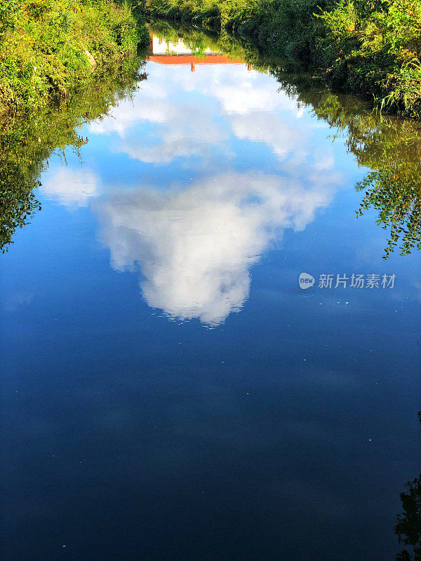 平静的运河水面上的家的倒影