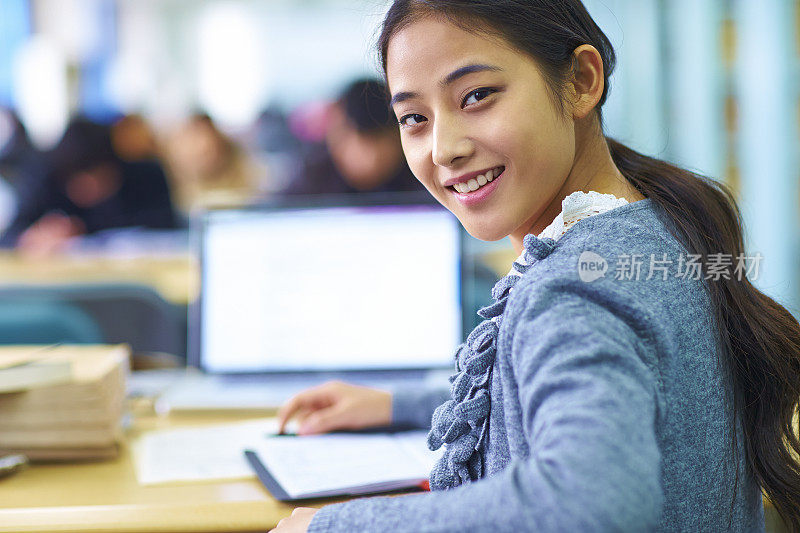 一个年轻漂亮的亚洲大学生在图书馆学习