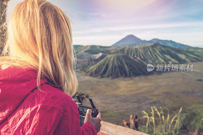 年轻女子使用无人机飞越火山景观——新科技人们旅游的概念