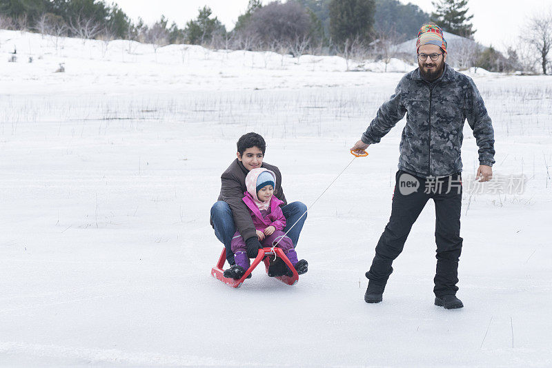 父亲带着孩子们玩雪橇