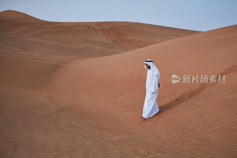 一个阿拉伯人在黎明时走在沙漠里