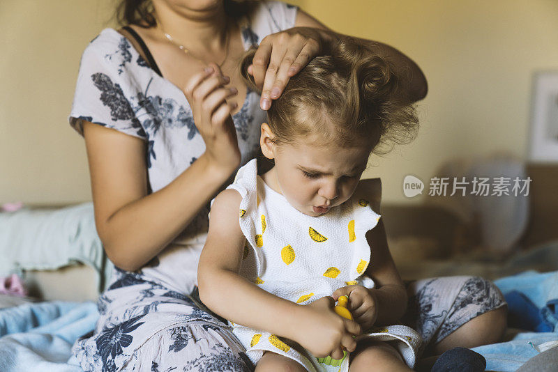 母亲做头发的学步女孩