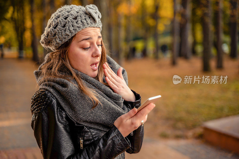 惊讶或震惊的女孩在户外使用她的智能手机