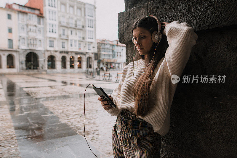 在城市里戴着耳机的年轻女子