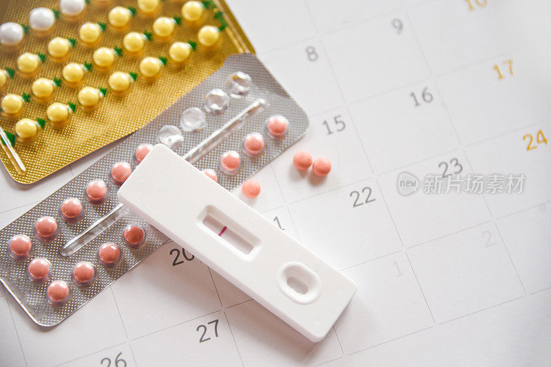 避孕药丸和怀孕测试预防怀孕避孕概念避孕用避孕套和日历上的玫瑰
