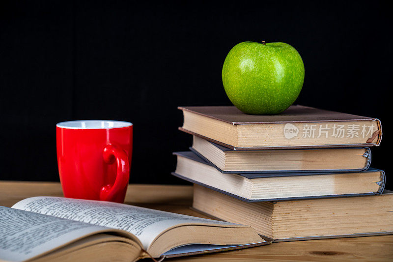 回到学校。书，绿苹果，铅笔和眼镜放在木桌上