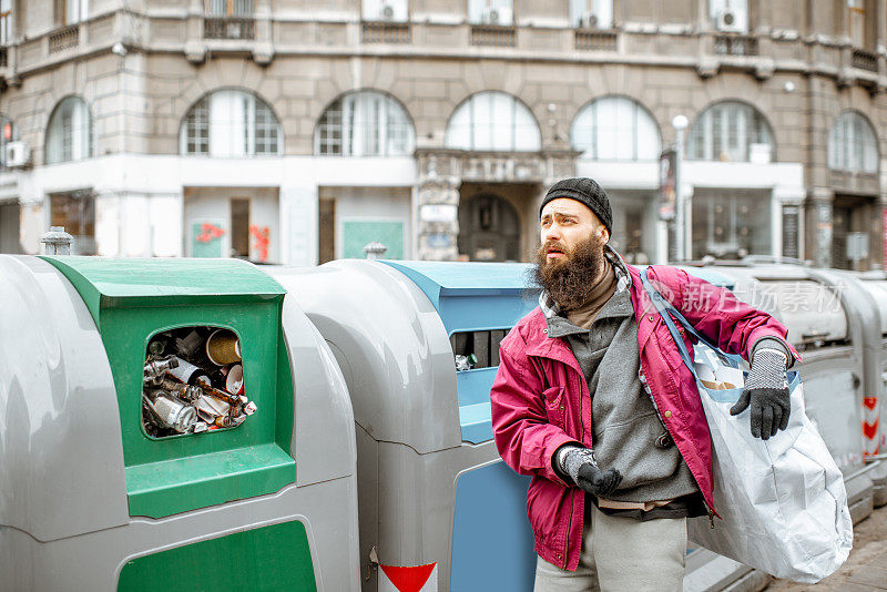 无家可归的乞丐靠近城市的垃圾箱