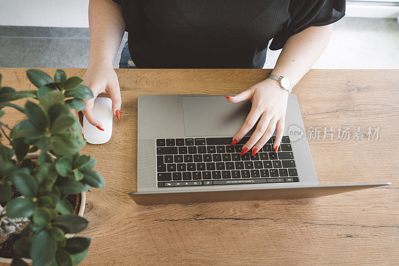 红指甲的女人在笔记本电脑上打字