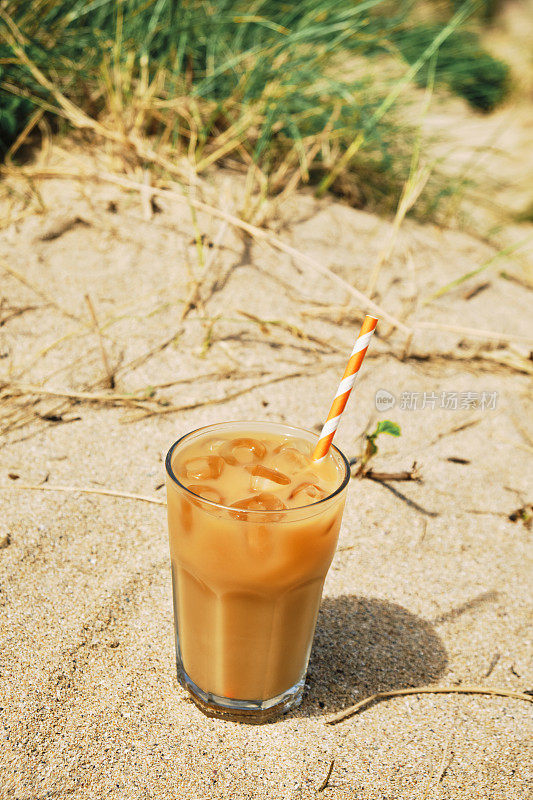 在一个炎热阳光明媚的夏日，在纽基菲斯特拉海滩的沙丘上喝一杯加牛奶的冰咖啡。