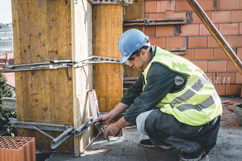 建筑工人用填缝枪在建筑工地施工