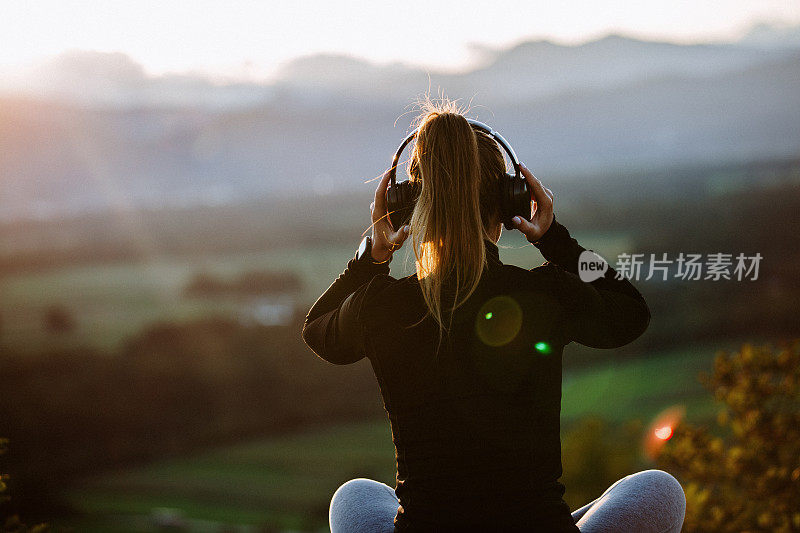 女孩戴着耳机在夕阳下听音乐