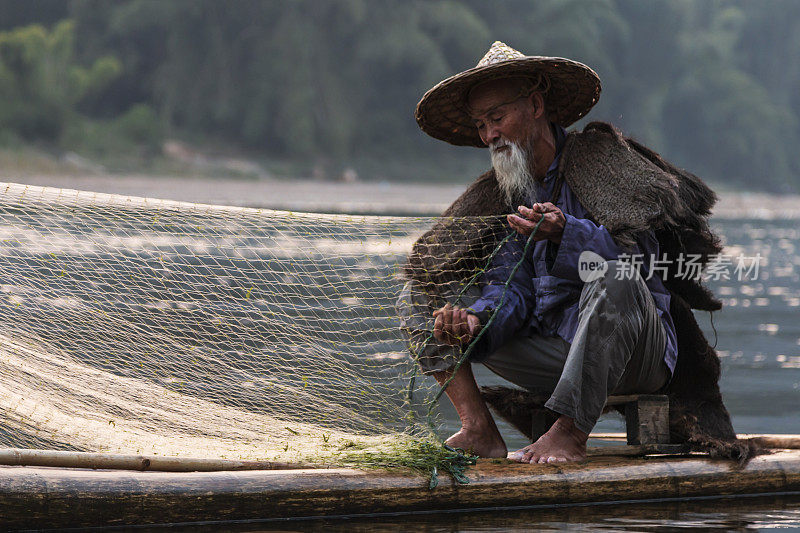肖像鸬鹚渔民在日落使用传统的捕鱼方法捕捉鱼在河里