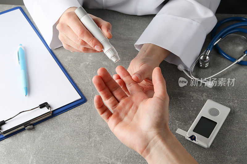 医生在灰色的桌子上检查糖尿病患者的血糖水平