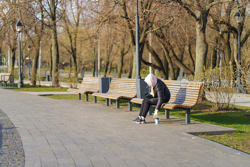 在城市公园里喝着咖啡抽着烟休息的女人