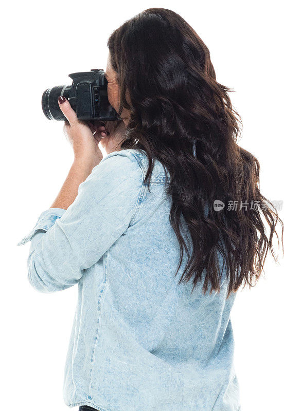 白人中年女性摄影师站着，穿着裤子，拿着相机