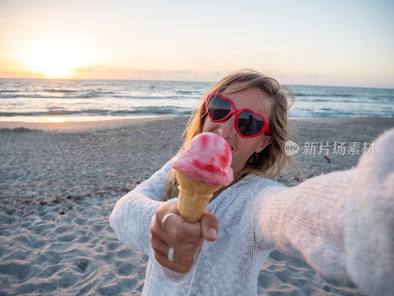夏日里，快乐的女人在海滩上吃冰淇淋，戴着心形眼镜