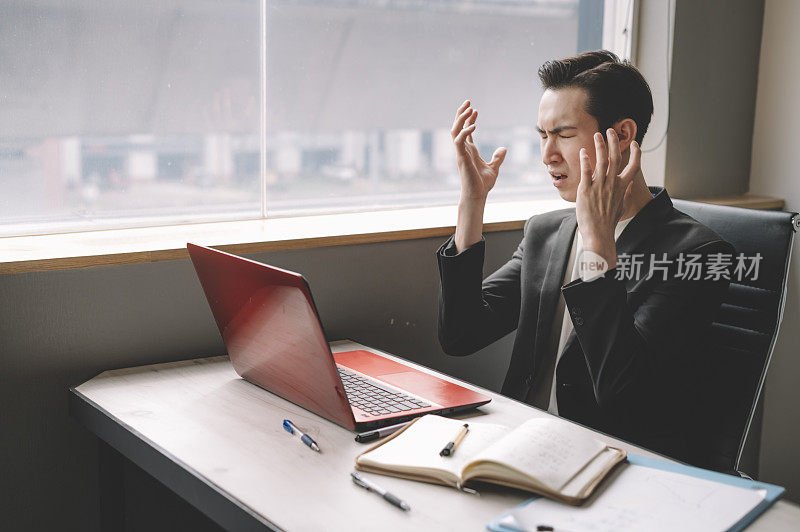 一个亚洲华裔年轻白领沮丧和情绪压力坐在他的办公室椅子上