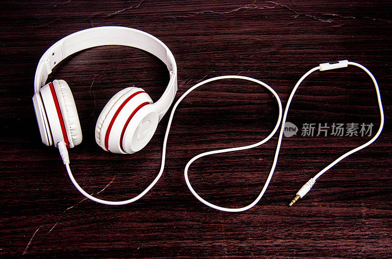 红白耳机放在木地板上放松音乐。运动、享受、放松