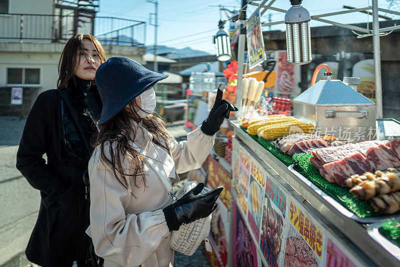 两名年轻美丽的女游客购买当地街头小吃的镜头
