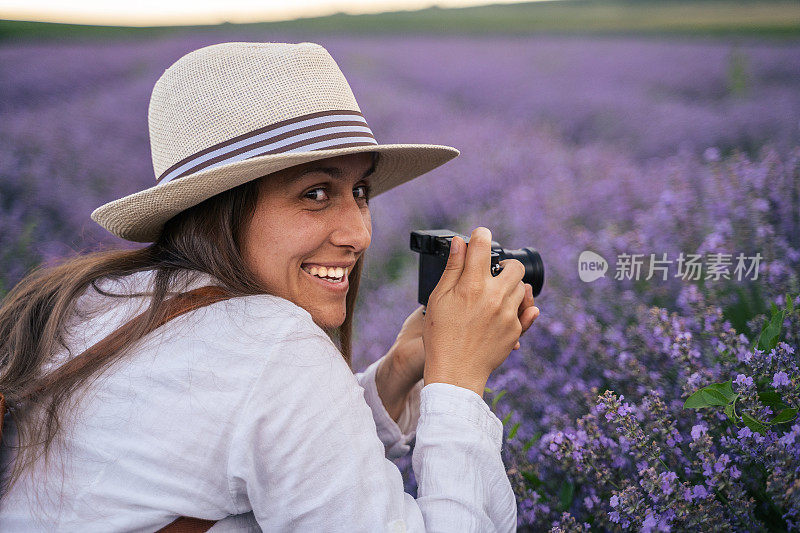 年轻的女游客在盛开的薰衣草地里拍照。旅游热。