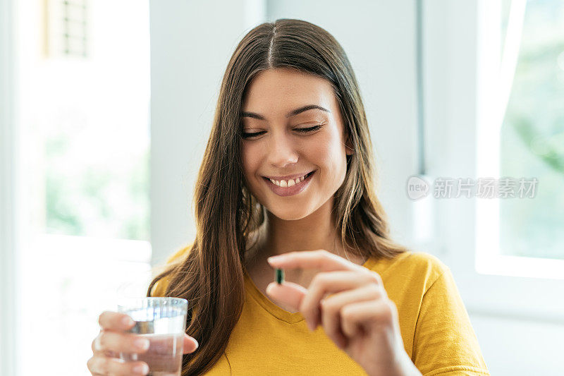 健康的年轻妇女服用草药补充和微笑