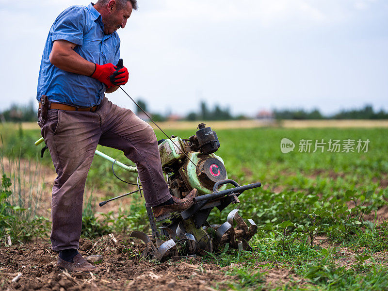 一位男性农民用一辆汽油步式拖拉机犁地