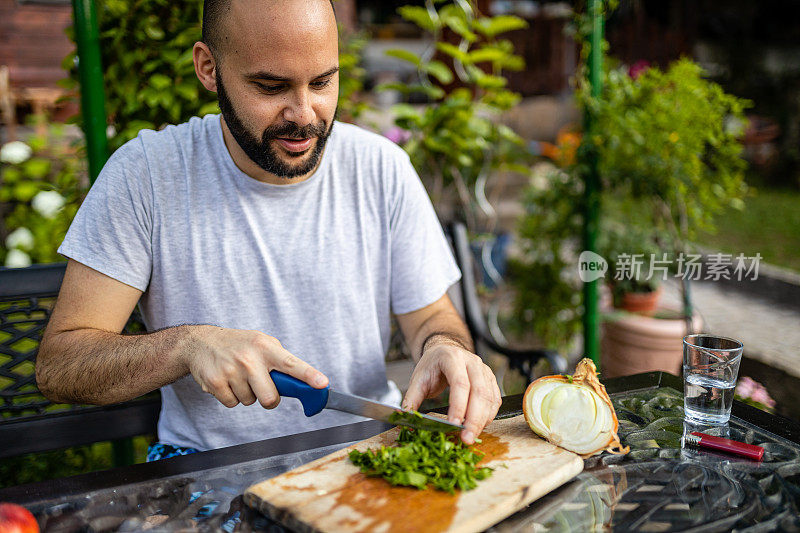 男人在自家后院切欧芹做饭