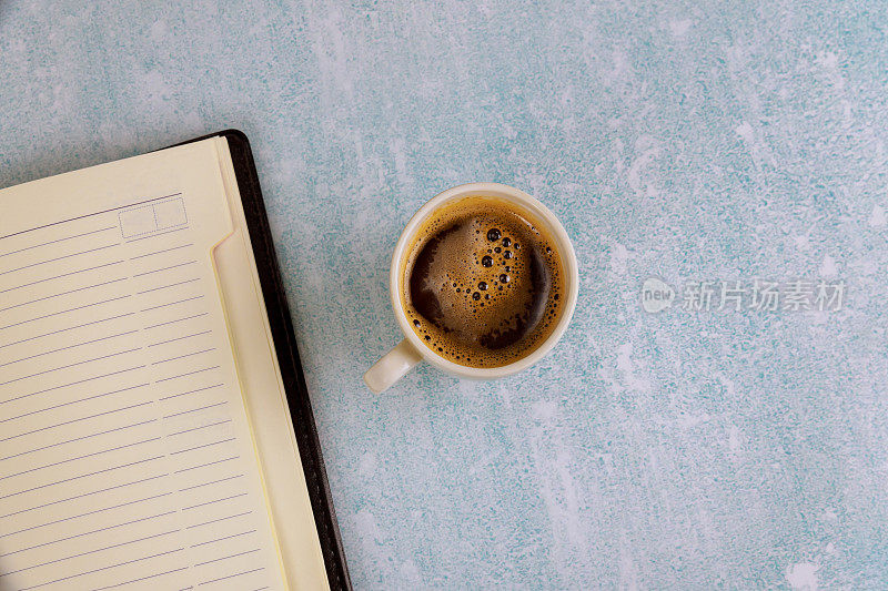 咖啡杯和每周记事本，规划和设计从上面到办公桌