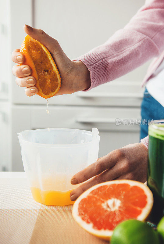 女孩的手挤压着橙子，在家里制作新鲜果汁