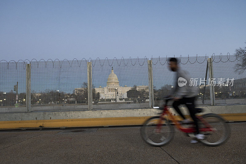 骑自行车经过华盛顿特区美国国会大厦周围的围栏和铁丝网