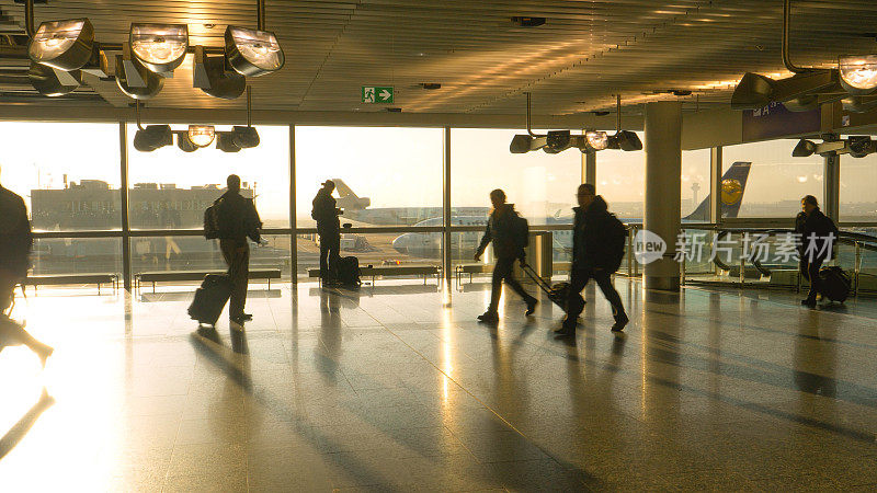 剪影:汉莎航空公司的飞机在跑道上滑行，旅客们在机场周围匆忙穿梭