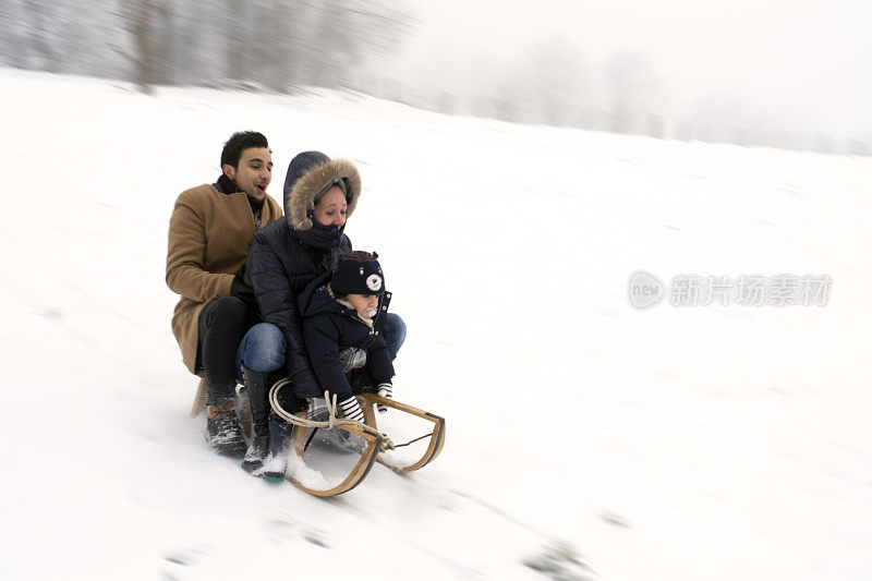 三个人坐在雪地里的木制雪橇上