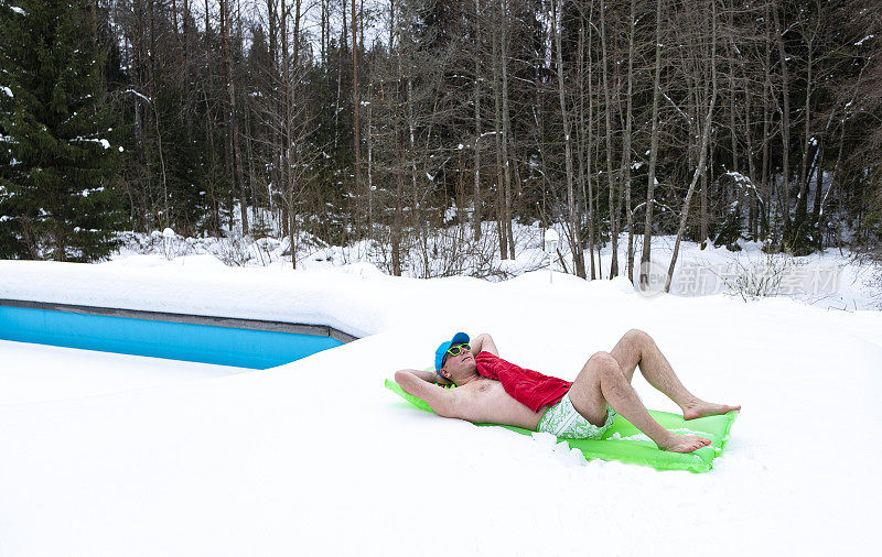 一个男人穿着泳裤，戴着墨镜，躺在一个充气床垫上。寒假在家。周末在别墅。